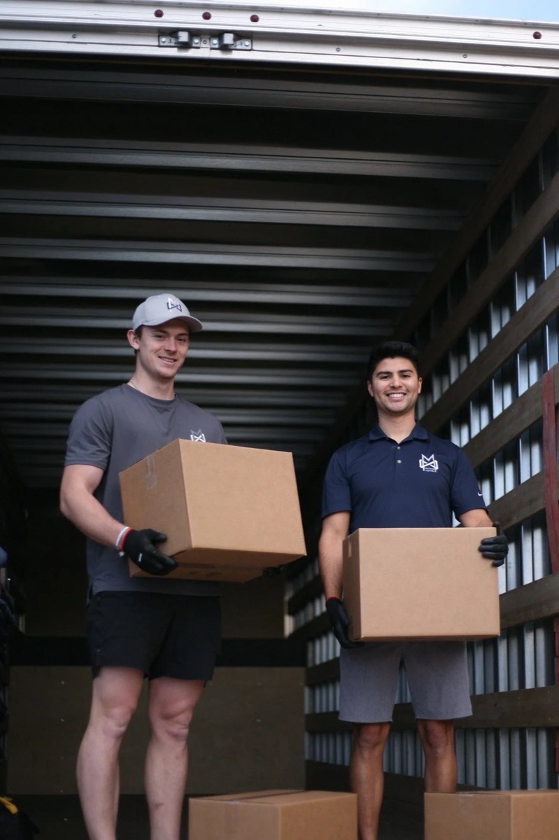 Two Limitless movers standing in the truck holding moving boxes