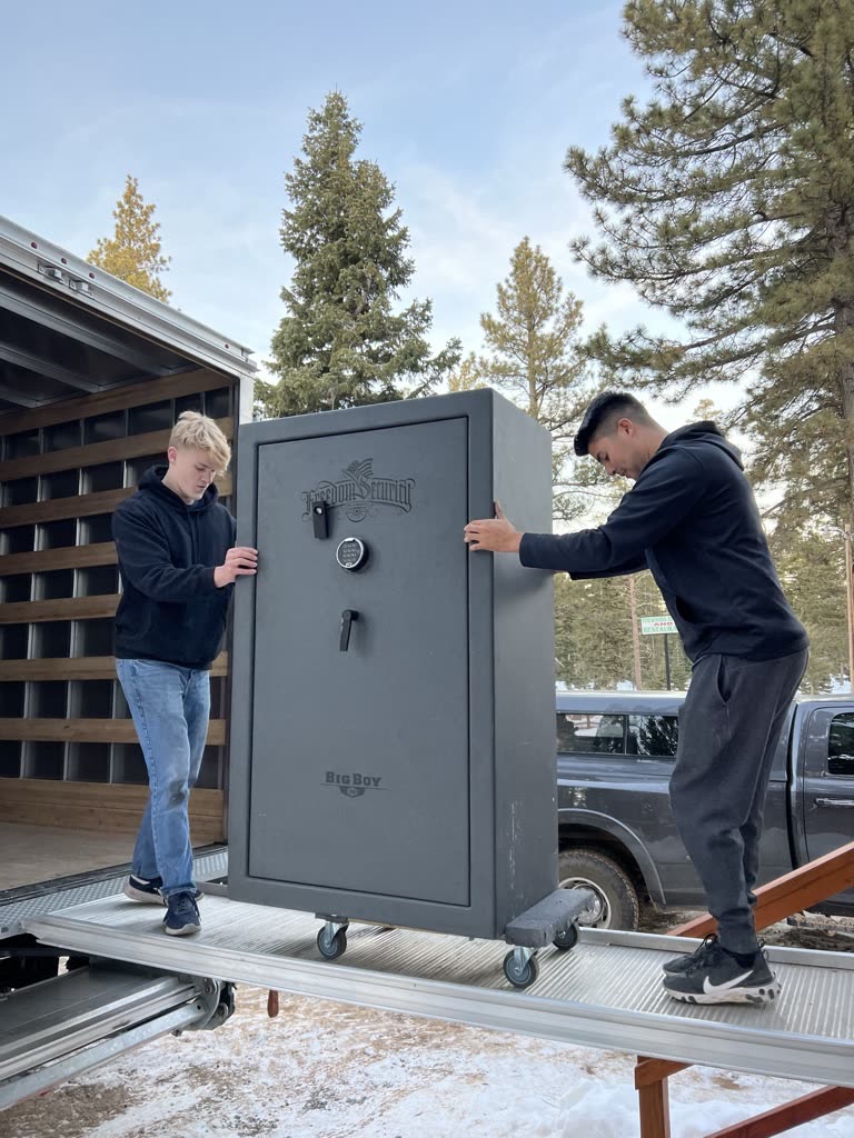 Two movers steadying a safe on the lift